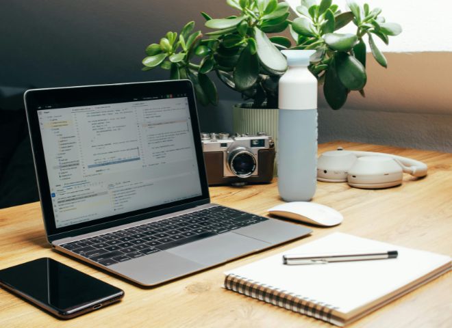 Uredan radni sto sa laptopom, beležnicom, telefonom i osnovnim kancelarijskim priborom, bez suvišnih predmeta i vizuelnog nereda.